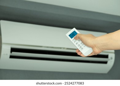 Man's hand using remote control open The air conditioner is cooled to 25 degrees Celsius in his bedroom. Health concepts and energy savings