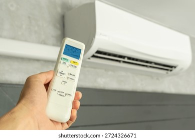 Man's hand using remote control open The air conditioner is cooled to 25 degrees Celsius in his bedroom. Health concepts and energy savings