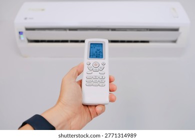 Man's hand using remote control open The air conditioner is cooled to 25 degrees Celsius in his bedroom. Health concepts and energy savings