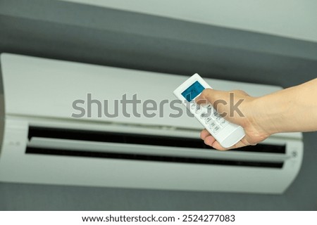 Man's hand using remote control open The air conditioner is cooled to 25 degrees Celsius in his bedroom. Health concepts and energy savings