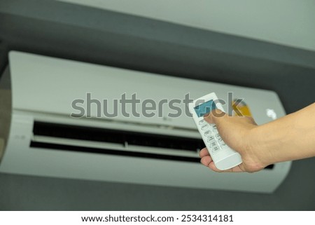 Man's hand using remote control open The air conditioner is cooled to 25 degrees Celsius in his bedroom. Health concepts and energy savings
