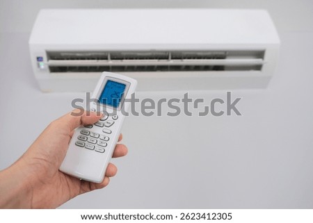 Man's hand using remote control open The air conditioner is cooled to 25 degrees Celsius in his bedroom. Health concepts and energy savings