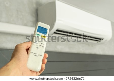 Man's hand using remote control open The air conditioner is cooled to 25 degrees Celsius in his bedroom. Health concepts and energy savings