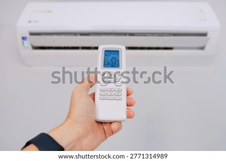 Man's hand using remote control open The air conditioner is cooled to 25 degrees Celsius in his bedroom. Health concepts and energy savings