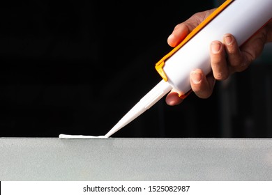 Man's Hand Is Using Silicone Glue Attached On Glass For General And Industrial Applications.