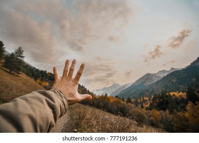 man's hand in a warm jacket against the backdrop of snowy mountains and forests. Human and nature. - Powered by Shutterstock