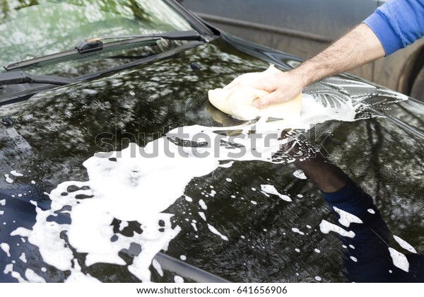 The man's hand washes the car's sponge mask with
plenty of foam.