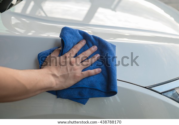 A man\'s hand wipe the car with microfiber\
cloth. Cleaning the car. Wipe off\
water.