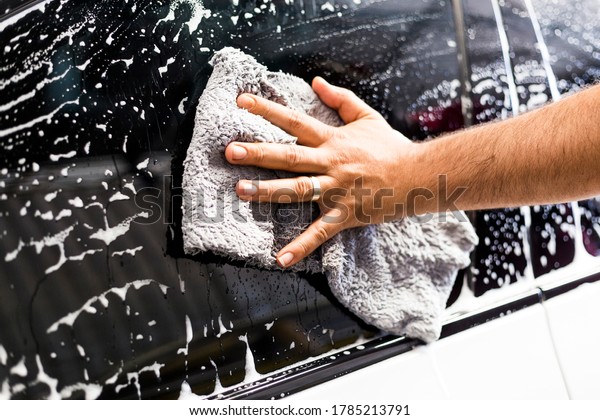 man\'s hand wiping the foamed\
car