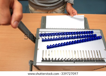 man's hands with binding pages at table.