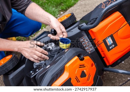 Man's hands checking a lawnmower engine in a garden. lawn mower maintenance, garden equipment service