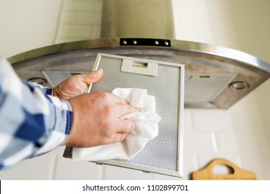 Man's hands cleaning aluminum mesh filter for cooker hood. Housework and chores. Kitchen cooker hood on the background