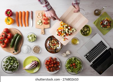 Man's Hands Cooking At Home And Chopping Fresh Vegetables On A Cutting Board, Kitchen Tools And Food Ingredients All Around, Top View