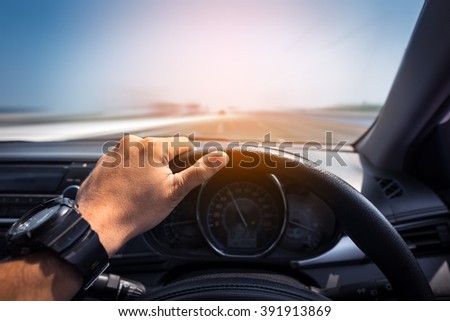 Man's hands of a driver on steering wheel of a minivan car on high way