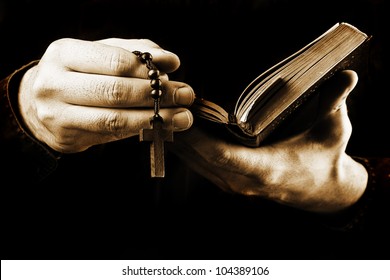 Man's Hands Holding Bible And Rosary During Prayer - Sepia Toned On Black Background