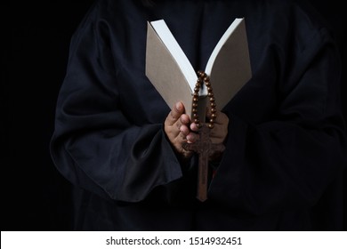 Man's Hands Holding Bible And Rosary During Prayer - On Black Background