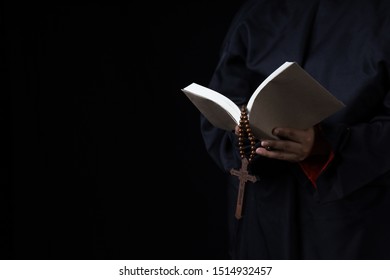 Man's Hands Holding Bible And Rosary During Prayer - Sepia Toned On Black Background