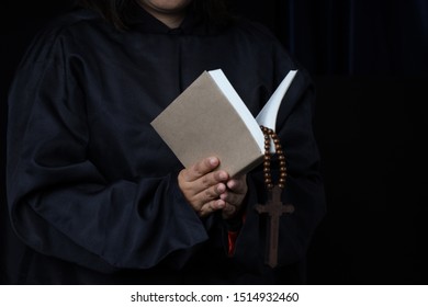 Man's Hands Holding Bible And Rosary During Prayer - Sepia Toned On Black Background