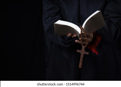 Man's Hands Holding Bible And Rosary During Prayer - Sepia Toned On Black Background