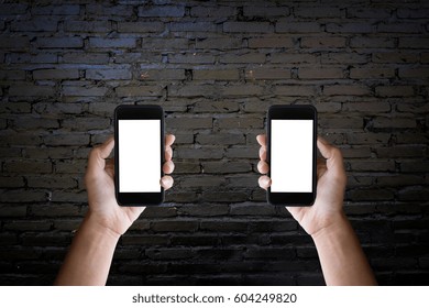 Man's Hands Holding Blank Screen Of A Smartphone At The Old Black Brick Wall.