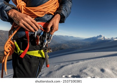 Man's hands holding snow climbing equipment, screws, carabiner, rope