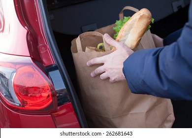 Mans Hands Loading A Shopping Bag In Car Trunk