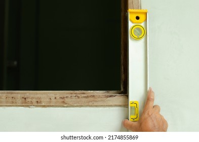 Man's Hands Measure A Wooden Windown Frame With A Spirit Level (bubble Level)