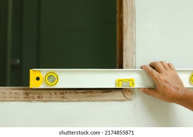 Man's Hands Measure A Wooden Windown Frame With A Spirit Level (bubble Level)