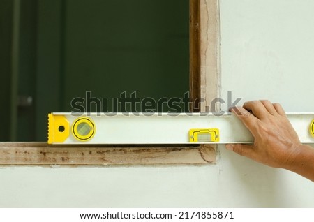 Man's hands measure a wooden windown frame with a spirit level (bubble level)