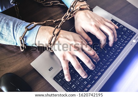Man's hands in old rusty chains. In the trap of office work. Routine job. Manager near the laptop.