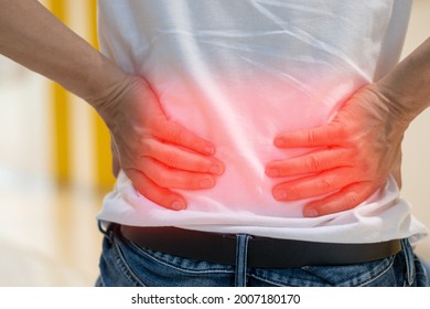Die Hände des Menschen auf dem Rücken mit rotem Fleck als Leiden auf Rückenschmerzen. Männliche Person krank vor Schmerzen im unteren Rücken von Hernisierten oder ausgespaltenen Scheiben, Degenerative, sacroiliale Gelenke, Rückenstenose, Pankreakarzinom