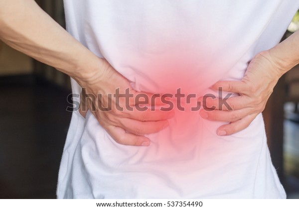 Man\'s hands on his back with red spot as suffering\
on backache. Male person sick from lower back pain from Herniated\
or slipped discs,Degenerative, sacroiliac joint, spinal stenosis,\
Pancreatic Cancer