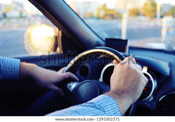 Man\'s hands on steering\
wheel.
