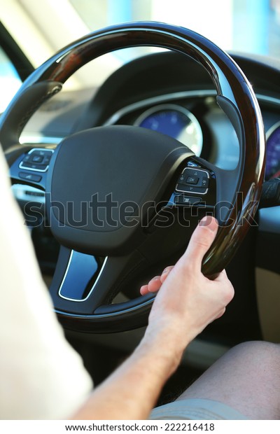 Man\'s hands on a steering\
wheel