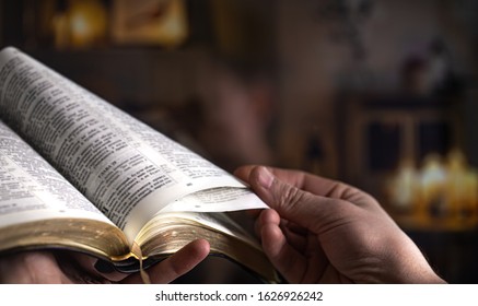 Man's Hands Over The Bible, Against The Background Of The Living Room. Close Up.