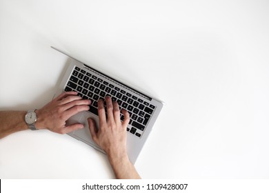 Man's Hands Over The Keyboard Of A Silver Laptop. Top View, With A Lot Of Negative Space.  