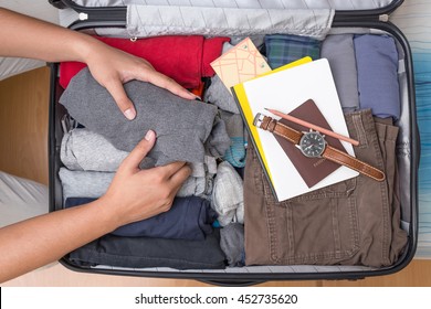 Man's Hands Are Pack Suitcase Bag For A Journey. Top View.