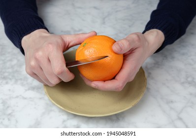 Man's Hands Peeling An Orange With A Knife. Healthy Food Concept