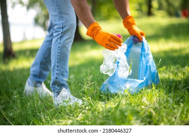 Mans hands picking up trash from grass - Shutterstock ID 2180446327