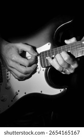 man's hands playing guitar strings