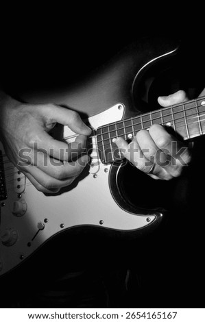 man's hands playing guitar strings