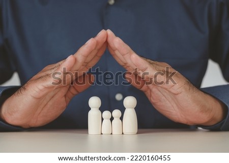 Man's hands protecting wooden figures of family members, Family relationship symbol, family home lockdown concept , Insurance and property investment, world mental health day. Wooden puppets.