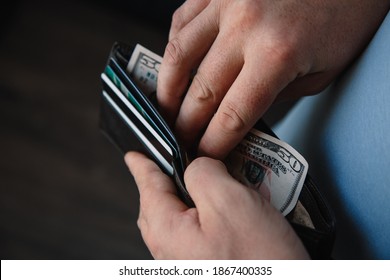 the man's hands put fifty-dollar bills in the wallet. Poverty concept, crisis. dismissal or cost savings