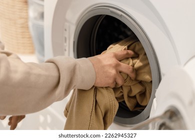 Man's hands putting clothes in the washing machine