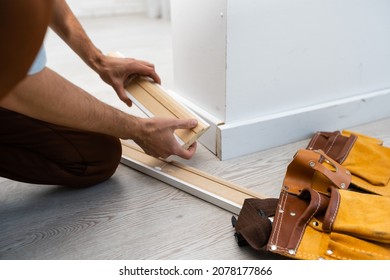 Mans Hands Putting White Baseboard.