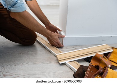 Mans Hands Putting White Baseboard.