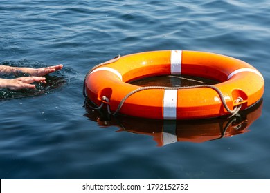 The man's hands reach for the lifebuoy in the water. The concept of saving drowning in reservoirs.