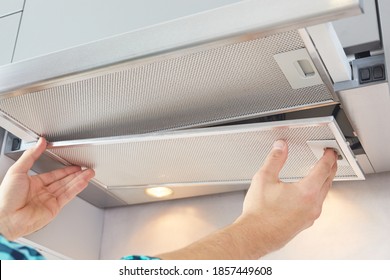 Mans Hands Removing A Filter From Cooker Hood For Cleaning Or Service. Replacing Filter In Kitchen Hood. Modern Kitchen Fan Or Range Hood.