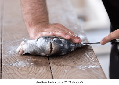 A Man's Hands Are Shown With A Sharp Filet Knife That He Is Using To Clean A Fish