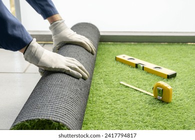 Man's hands spread an artificial turf roll at home - Powered by Shutterstock